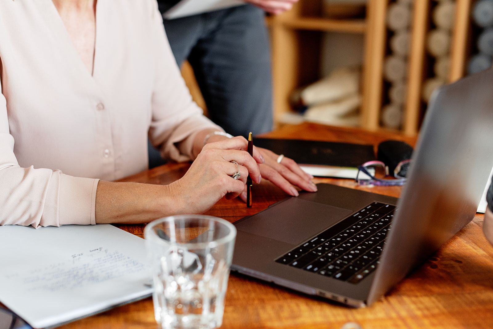 Close-up of a person working intently on a laptop with documents spread on the desk, illustrating a single owner accountable for signal response.