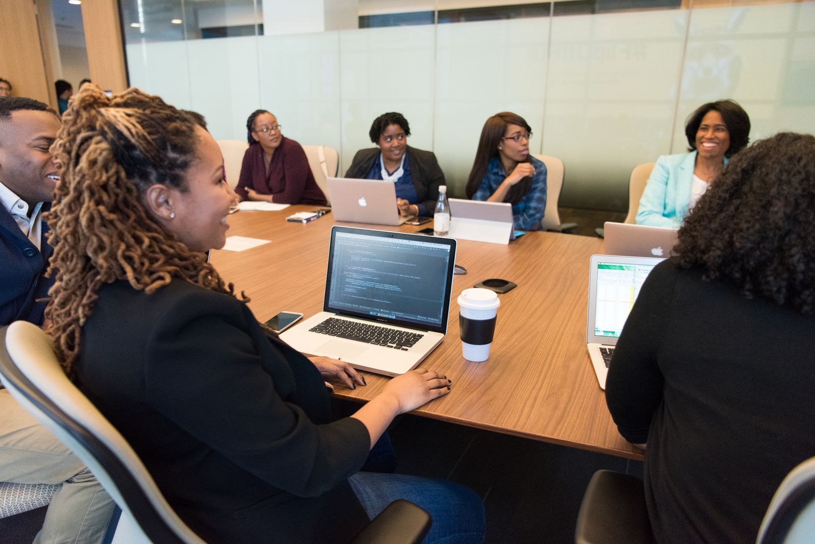 Diverse group of professionals working together around laptops in a modern conference room, illustrating the revenue team habits that make an intent programme work.